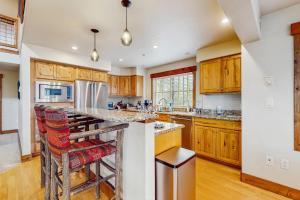 a kitchen with wooden cabinets and a island with bar stools at Pines at Orehouse 301 PH2 in Steamboat Springs