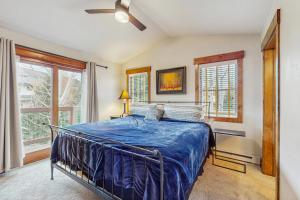 a bedroom with a bed with a blue comforter at Pines at Orehouse 301 PH2 in Steamboat Springs