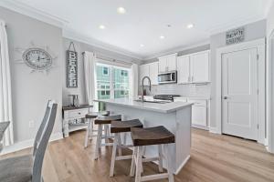 a kitchen with white cabinets and a island with bar stools at Waves & Wildlife Getaway at Summer Salt in Orange Beach