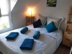 a white bed with blue pillows on top of it at Le cottage de Guidel in Guidel