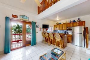 a kitchen with a bar with chairs and a refrigerator at Palm @ Caribe Island in San Pedro
