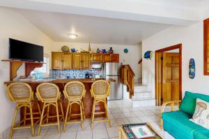 a kitchen with a bar with chairs and a couch at Palm @ Caribe Island in San Pedro