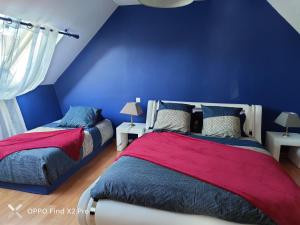 two beds in a room with a blue wall at Ti harmoniel in Guingamp