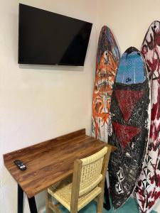 a tv hanging on a wall next to a surfboard at PointBreak Surfhouse in Puerto Escondido