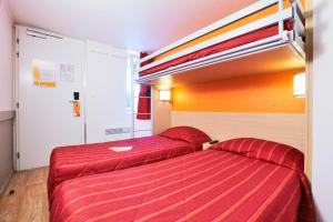 two beds in a hotel room with red sheets at Premiere Classe La Rochelle Nord - Puilboreau in Puilboreau