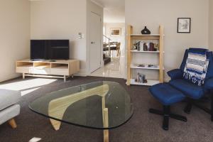 a living room with a glass table and a chair at City Sails - 3 BR townhouse in central New Plymouth in New Plymouth