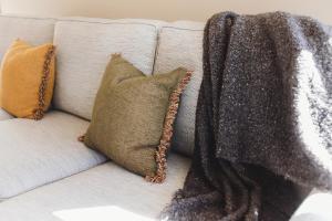a white couch with pillows and a blanket on it at City Sails - 3 BR townhouse in central New Plymouth in New Plymouth