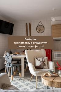 een woonkamer met een tafel en stoelen en een keuken bij Kominkowy Chill - prywatne zewnętrzne jacuzzi w wybranych apartamentach in Biały Dunajec