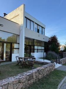 a building with a table and chairs in front of it at Apart Hotel El Molino de la Costa in Villa Carlos Paz