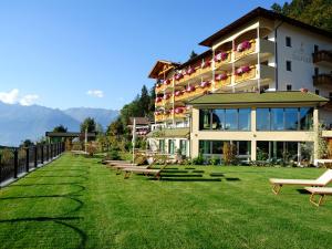 a large building with benches in the grass at Hotel Sulfner in Avelengo