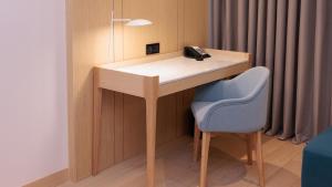 a wooden desk with a phone and a blue chair at Crowne Plaza Dushanbe by IHG in Dushanbe