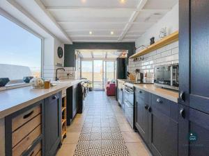 a kitchen with blue cabinets and a large window at Harvest Moon - cottage close to harbour in Weymouth