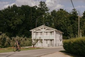 a person riding a bike in front of a white building at Tenuta delle Radici in Giavera del Montello