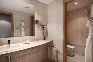 Un baño con lavabo, inodoro y espejo. en Hotel NH Ciudad Real, en Ciudad Real 19 fotos más