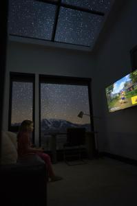 een jong meisje dat op een bank zit en naar de televisie kijkt bij Eagles Wings Luxe Yellowstone Retreat Condé Nast in Emigrant