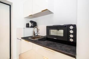 a kitchen with a microwave and a sink at Axxis Nova Beach in Mamaia