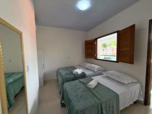 een slaapkamer met twee bedden en een raam bij MHV Milagres - Casa Lar do Marceneiro, Casa reservada e privativa a poucos metros da Praia do Marceneiro e da Capela in Passo de Camarajibe +78 foto's