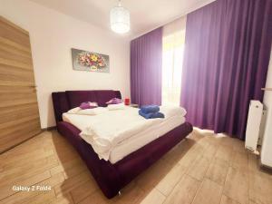 a bedroom with a bed with purple curtains at Luxury ApartHotel Alezzi Spa Resort Piscina Incalzita in Mamaia Nord +14 photos