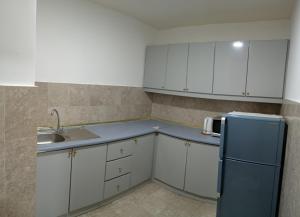 een keuken met witte kasten en een blauwe koelkast bij Eco suites at times square in Kuala Lumpur