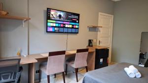 Una habitación con un escritorio y un televisor en la pared. en Quarto Plus Gonzaga, en Santos 3 fotos más