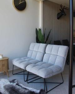 Un sofá azul en una sala de estar con un reloj. en Luxus Vendégház a Szigetköz szívében, en Dunasziget