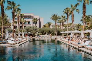 a pool at a resort with lounge chairs and palm trees at Four Seasons Resort Marrakech in Marrakech
