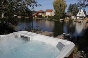 una bañera junto a un cuerpo de agua en Luxus Vendégház a Szigetköz szívében, en Dunasziget