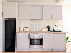 une cuisine avec des armoires blanches et un réfrigérateur noir dans l'établissement Garden Apartment with Private Entrance, à Dublin