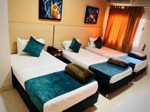 a room with three beds with pillows on them at Hotel Luxor Cúcuta in Cúcuta