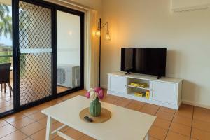 una sala de estar con TV y un jarrón sobre una mesa en Paradise on Palmer-City Stadium Ferry&Strand in Townsville, en Townsville 1 foto más