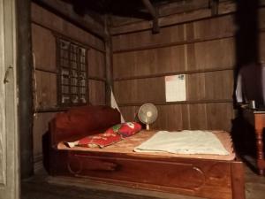 a bed in a room with a wooden wall at Sconvolt Homestay in Kratie