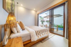 a bedroom with a bed and a large window at Cassandra Villa 1 - Family Paradise in Sanur