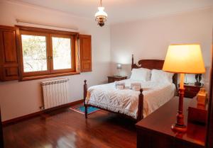 ein Schlafzimmer mit einem Bett mit einer Lampe und einem Fenster in der Unterkunft Casa Das Flores in Bouro + 32 Fotos