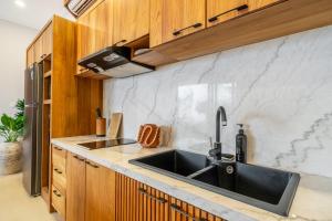 a kitchen with a black sink and wooden cabinets at Cassandra Villa 1 - Family Paradise in Sanur