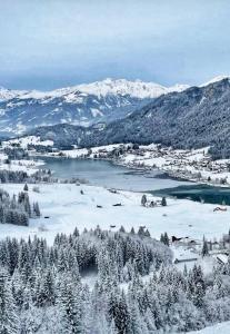 a view of a town with snow covered mountains at SeeHotel & SeeApartments Kärntnerhof- direkt am See! in Weissensee +159 photos