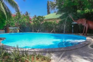a blue swimming pool with a dinosaur statue next to it at Florlaleona Villa in Malindi