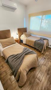 two beds in a room with wooden floors at Los Carpinchos: Duplex in Federación