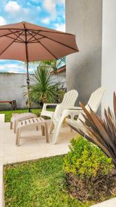 two chairs and an umbrella on a patio at Los Carpinchos: Duplex in Federación +54 photos
