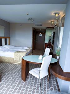 ein Zimmer mit einem Bett und einem Tisch und Stühlen in der Unterkunft ABSea Marine Hotel Apartament z widokiem na morze in Kołobrzeg + 8 Fotos