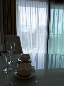 einen Esstisch mit Gläsern und Tellern sowie ein Fenster in der Unterkunft ABSea Marine Hotel Apartament z widokiem na morze in Kołobrzeg