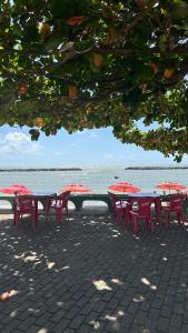 eine Reihe roter Tische und Stühle neben dem Wasser in der Unterkunft Janga Paulista-Pe in Paulista + 8 Fotos