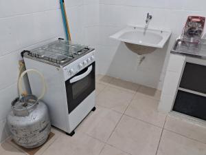 une cuisine avec une cuisinière et un évier dans l'établissement Apto 2 quartos Grã Duquesa, à Governador Valadares