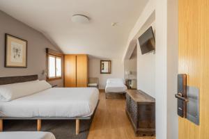 a hotel room with two beds and a tv at Hotel Rural Izar Ondo in Arbizu
