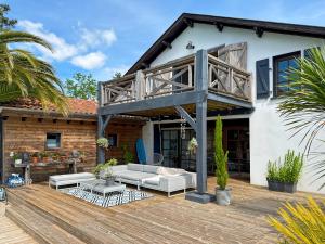 a house with a deck with a couch and a balcony at La Belle Landaise 1809 Gîte Arridoulet 1 in Peyrehorade