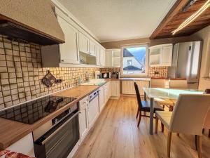 a kitchen with white cabinets and a table and a dining room at White Pearl Apartment in Murau +26 photos