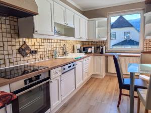 a kitchen with white cabinets and a table and a window at White Pearl Apartment in Murau