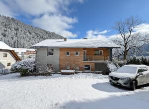 a car parked in front of a house in the snow at White Pearl Apartment in Murau