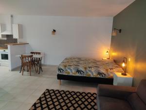 a bedroom with a bed and a kitchen with a table at Médis Royan Saujon in Médis