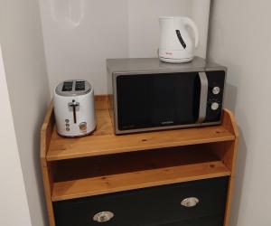 a microwave sitting on top of a wooden shelf at Médis Royan Saujon in Médis +2 photos