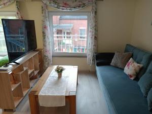 a living room with a blue couch and a tv at NEU! Ferienwohnung Storchennest OG in Pömmelte +3 photos